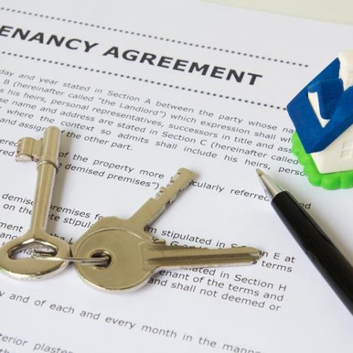 Tenancy agreement, key and pen with symbolic miniature house